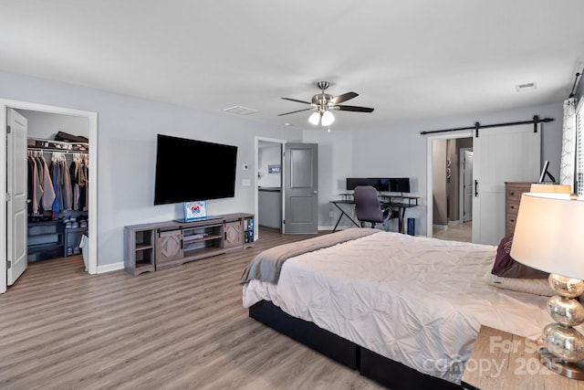 1725 Mill Creek Ln SW, Concord, NC 28025 - bedroom with baseboards, a walk in closet, a barn door, wood finished floors, and a closet