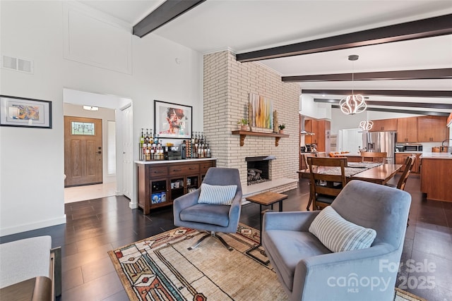 225 Valley View Ter, Waynesville, NC 28786 - living room featuring beamed ceiling, a brick fireplace, a chandelier, and dark wood-style flooring
