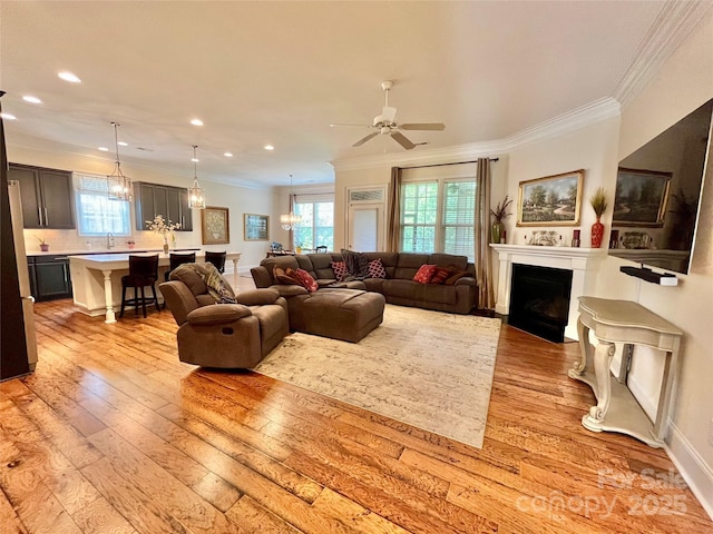 1025 N Sharon Amity Rd, Charlotte, NC 28211 - living room with ornamental molding, a fireplace with flush hearth, light wood finished floors, a chandelier, and ceiling fan