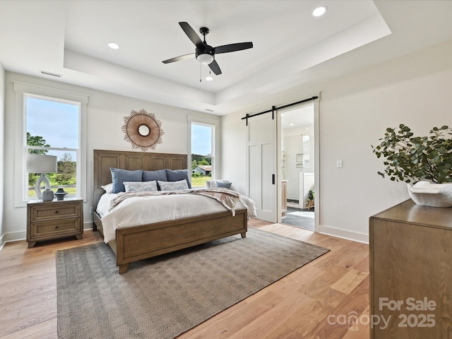 1172 Springlake Rd, York, SC 29745 - bedroom with a tray ceiling, a barn door, light wood-style floors, recessed lighting, and baseboards