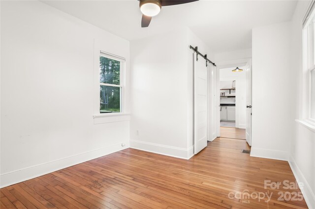17 Springdale Ave, Asheville, NC 28803 - spare room featuring a barn door, ceiling fan, light wood-style flooring, and baseboards