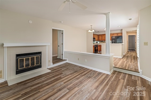 302 NW Dr, Davidson, NC 28036 - unfurnished living room with wood finished floors, a fireplace, ceiling fan, and ornate columns