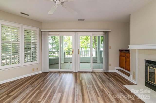 302 NW Dr, Davidson, NC 28036 - unfurnished living room featuring healthy amount of natural light, a tiled fireplace, and wood finished floors