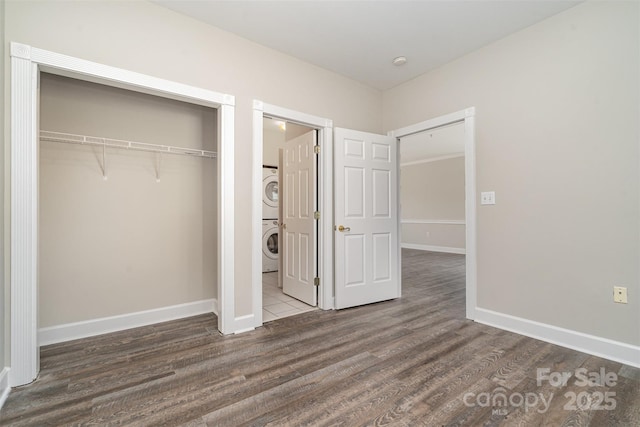 8969 Meadow Vista Rd, Charlotte, NC 28213 - unfurnished bedroom featuring estacked washer and dryer, wood finished floors, a closet, and baseboards