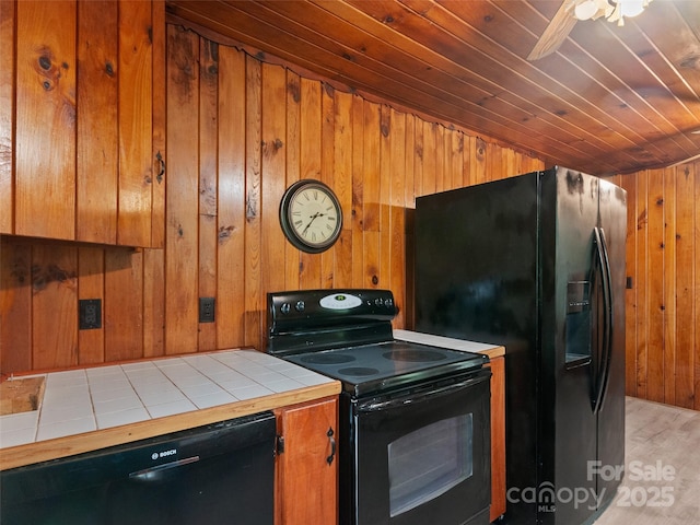 49 Caring Place Loop, Clyde, NC 28721 - kitchen featuring black appliances, tile counters, wooden walls, brown cabinetry, and light wood-style floors
