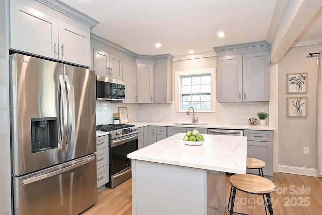 532 Scaleybark Rd, Charlotte, NC 28209 - kitchen with appliances with stainless steel finishes, a sink, gray cabinets, a kitchen bar, and ornamental molding