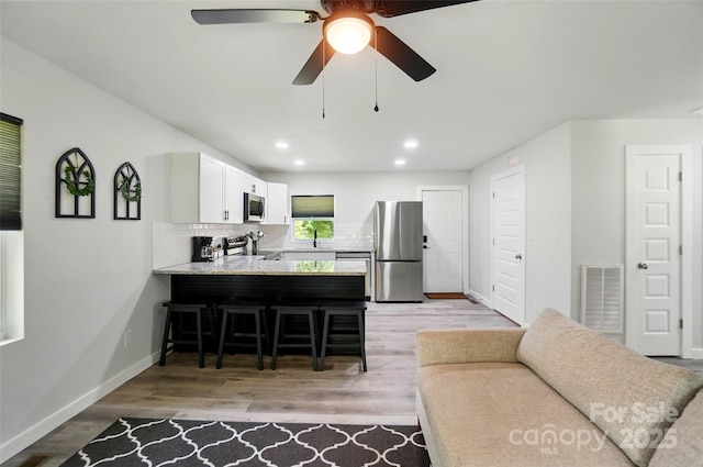 13821 David St, Huntersville, NC 28078 - kitchen featuring stainless steel appliances, a breakfast bar, a peninsula, backsplash, and light countertops