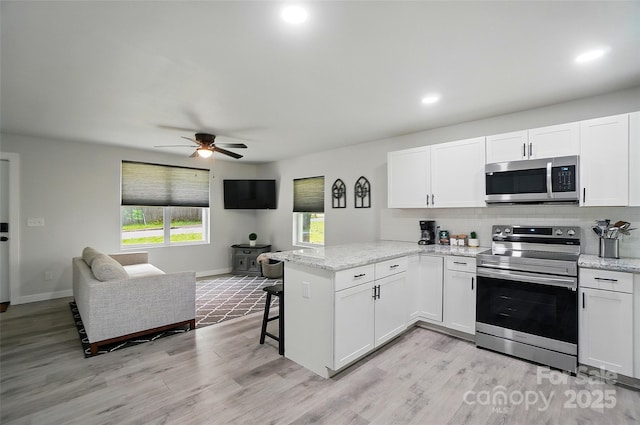 13821 David St, Huntersville, NC 28078 - kitchen with stainless steel appliances, a peninsula, open floor plan, white cabinetry, and a ceiling fan