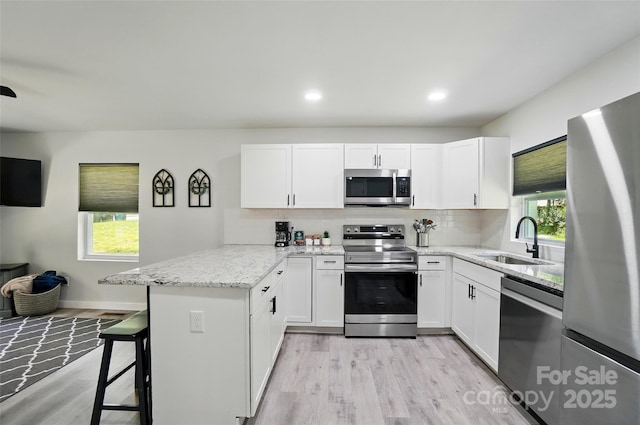 13821 David St, Huntersville, NC 28078 - kitchen featuring appliances with stainless steel finishes, a sink, a peninsula, light wood finished floors, and recessed lighting
