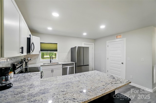 13821 David St, Huntersville, NC 28078 - kitchen featuring stainless steel appliances, a sink, a peninsula, light stone counters, and wood finished floors