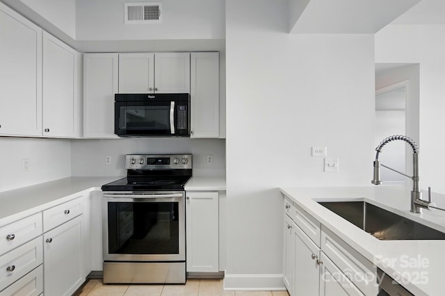 1315 E Blvd Unit 611, Charlotte, NC 28203 - kitchen featuring black microwave, stainless steel range with electric stovetop, light countertops, white cabinets, and light tile patterned floors