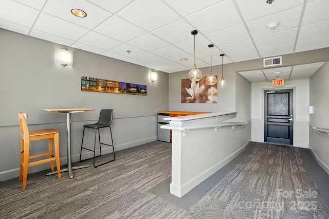 1315 E Blvd Unit 611, Charlotte, NC 28203 - kitchen with a breakfast bar, a paneled ceiling, a peninsula, dark colored carpet, and pendant lighting