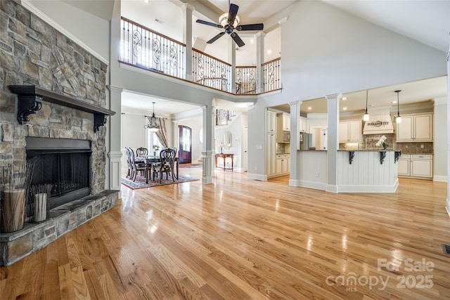546 Little Cove Ln, Lake Wylie, SC 29710 - living area featuring ornate columns, light wood-style flooring, a ceiling fan, a towering ceiling, and a stone fireplace