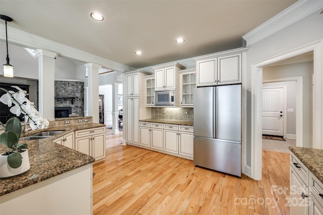 546 Little Cove Ln, Lake Wylie, SC 29710 - kitchen featuring stainless steel appliances, ornate columns, ornamental molding, a fireplace, and light wood finished floors