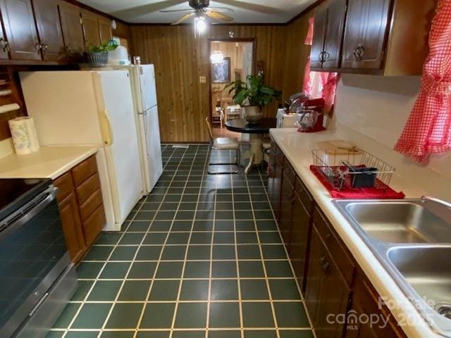 13427 Homewood Dr, Charlotte, NC 28262 - kitchen featuring a sink, wood walls, stainless steel electric range oven, ceiling fan, and light countertops