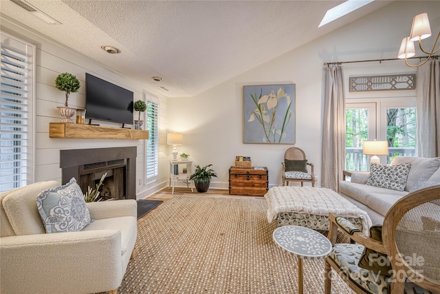 206 Independence Trl, Morganton, NC 28655 - living room with vaulted ceiling, a skylight, wood finished floors, a fireplace, and a textured ceiling
