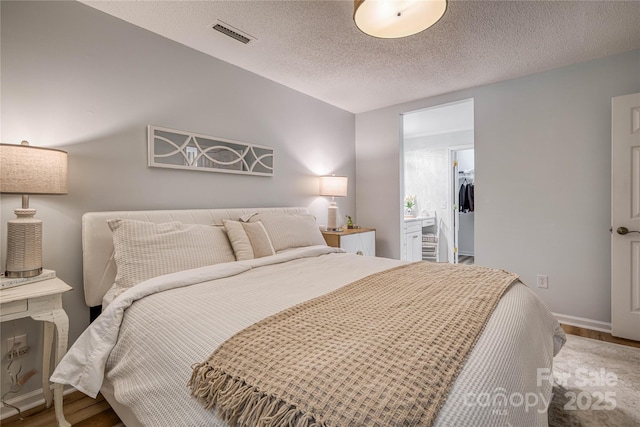 206 Independence Trl, Morganton, NC 28655 - bedroom featuring wood finished floors, a textured ceiling, a walk in closet, and baseboards