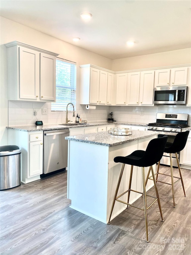 7024 Wheyfield Dr, Charlotte, NC 28215 - kitchen featuring appliances with stainless steel finishes, a sink, light wood-type flooring, and a kitchen island
