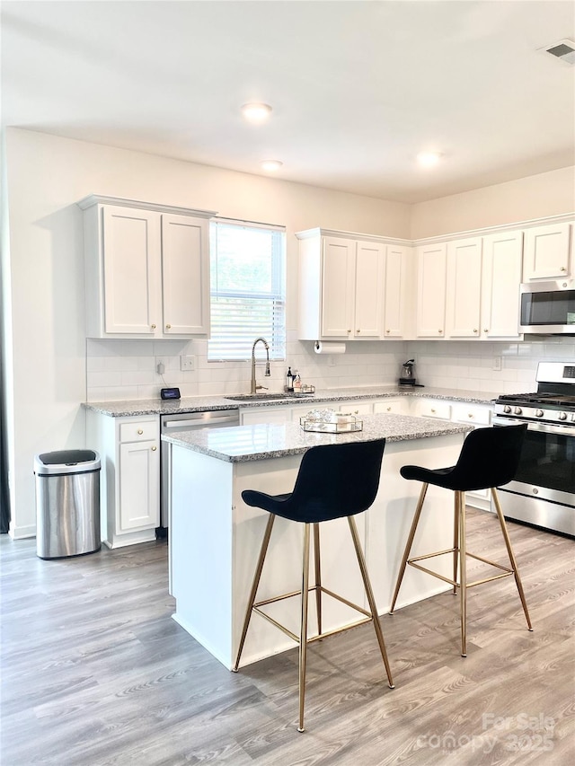 7024 Wheyfield Dr, Charlotte, NC 28215 - kitchen featuring appliances with stainless steel finishes, a sink, a kitchen bar, decorative backsplash, and a kitchen island