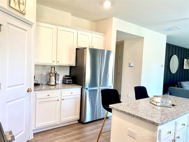 7024 Wheyfield Dr, Charlotte, NC 28215 - kitchen with freestanding refrigerator, white cabinets, light wood-style floors, and light stone counters