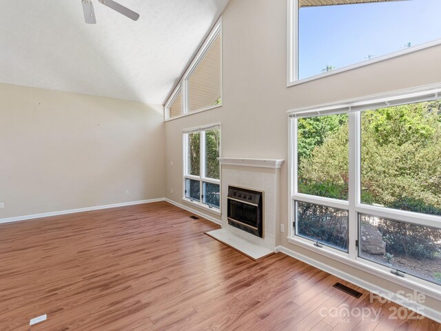 18 Westbridge Dr, Hendersonville, NC 28739 - unfurnished living room with high vaulted ceiling, a tile fireplace, wood finished floors, a ceiling fan, and baseboards