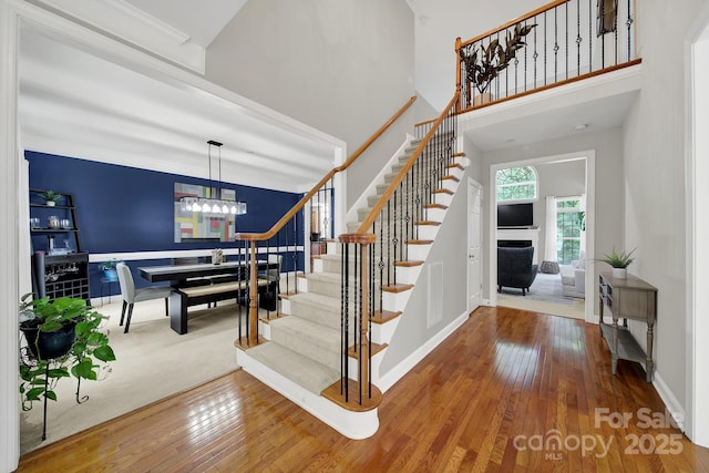 16714 Hammock Creek Pl, Charlotte, NC 28278 - stairs featuring wood-type flooring, a chandelier, a fireplace, a towering ceiling, and baseboards
