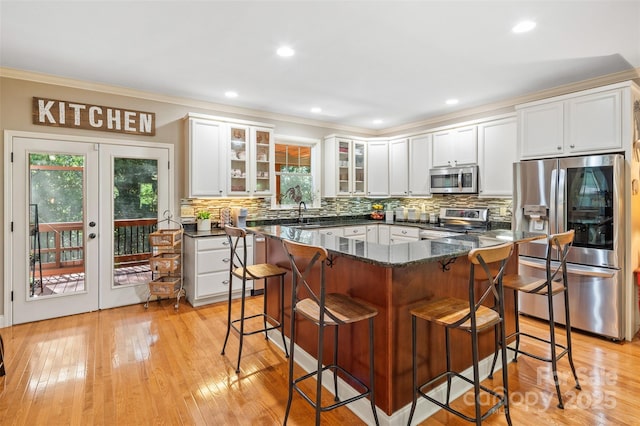 51 Cherry Ridge Ln, Weaverville, NC 28787 - kitchen featuring stainless steel appliances, a kitchen breakfast bar, white cabinetry, decorative backsplash, and glass insert cabinets