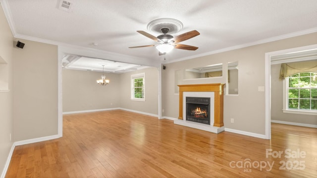 8321 Walkup Rd, Waxhaw, NC 28173 - unfurnished living room with a warm lit fireplace, ceiling fan, a chandelier, wood finished floors, and crown molding