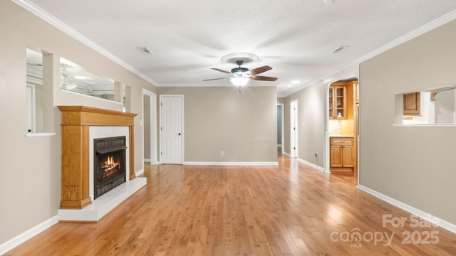 8321 Walkup Rd, Waxhaw, NC 28173 - unfurnished living room with a ceiling fan, a tiled fireplace, light wood-style flooring, crown molding, and a textured ceiling