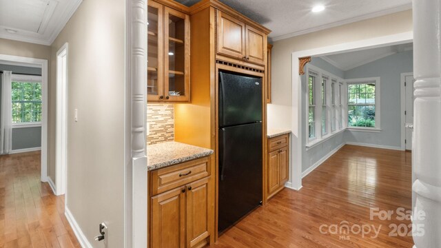 8321 Walkup Rd, Waxhaw, NC 28173 - kitchen with freestanding refrigerator, light wood-style flooring, ornamental molding, backsplash, and glass insert cabinets