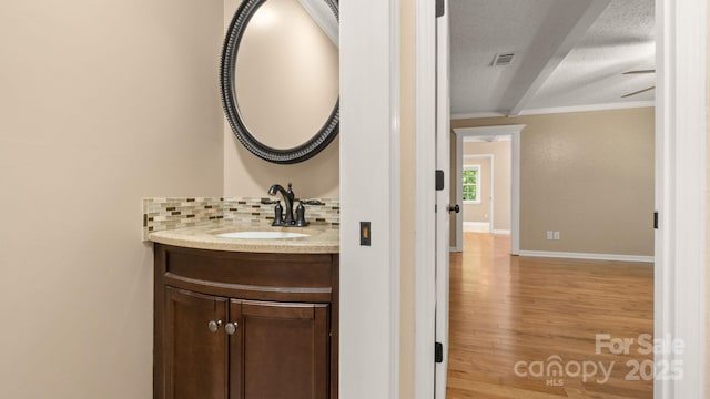 8321 Walkup Rd, Waxhaw, NC 28173 - bathroom featuring a textured ceiling, vanity, crown molding, wood finished floors, and decorative backsplash