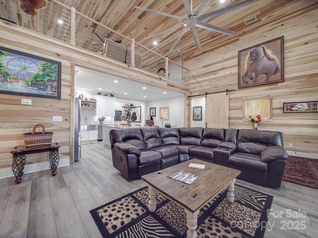 574 Crescent Rd, Rockwell, NC 28138 - living area featuring a barn door, wood walls, high vaulted ceiling, light wood finished floors, and ceiling fan