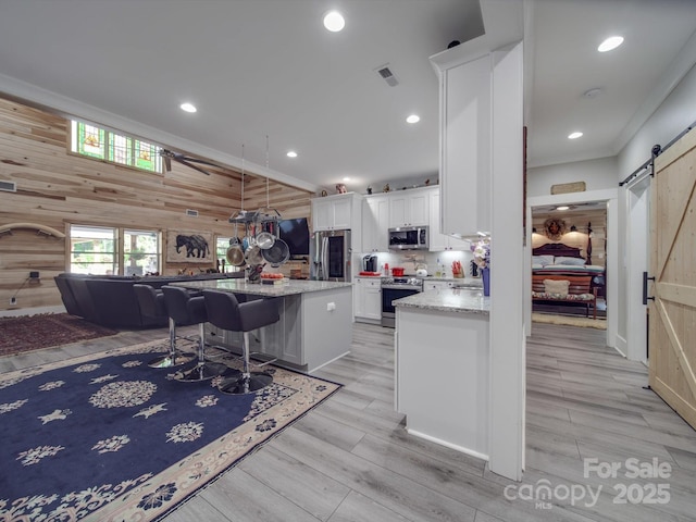 574 Crescent Rd, Rockwell, NC 28138 - kitchen featuring appliances with stainless steel finishes, a barn door, wooden walls, white cabinetry, and a center island