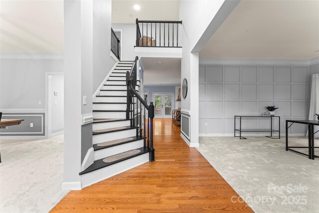 6432 Morningsong Ln, Charlotte, NC 28269 - carpeted foyer featuring stairs, ornamental molding, a decorative wall, baseboards, and wood finished floors