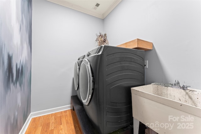 6432 Morningsong Ln, Charlotte, NC 28269 - laundry area featuring washing machine and dryer, light wood-style floors, ornamental molding, and baseboards