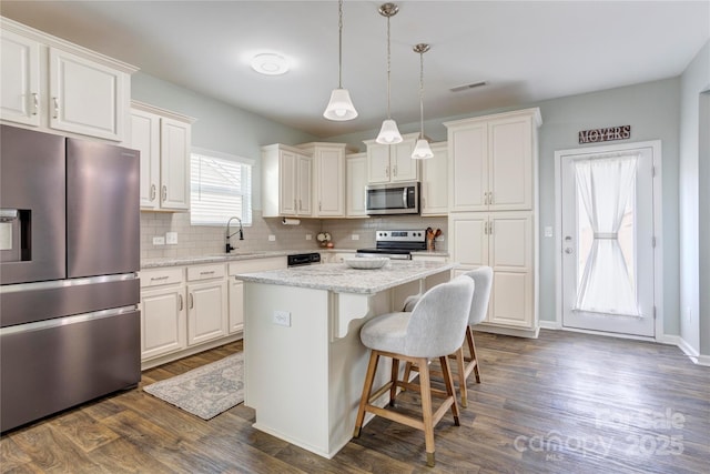1077 River Haven Ave SW, Concord, NC 28025 - kitchen featuring appliances with stainless steel finishes, a center island, tasteful backsplash, white cabinetry, and dark wood-style floors
