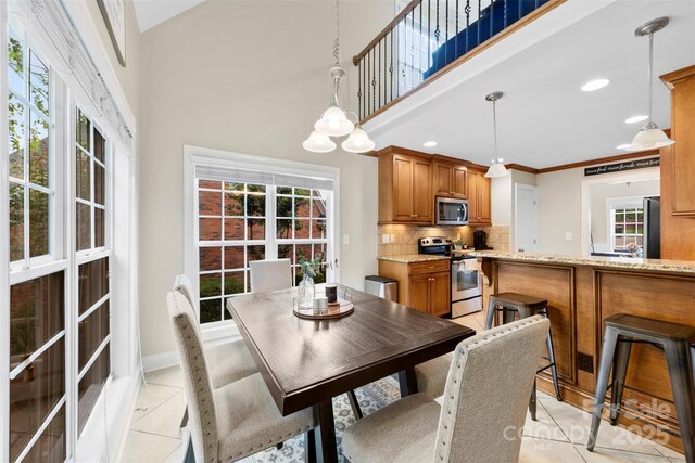 2563 Firethorn Ct, Gastonia, NC 28056 - dining room with light tile patterned floors, a towering ceiling, and baseboards