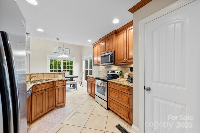 2563 Firethorn Ct, Gastonia, NC 28056 - kitchen with stainless steel appliances, a sink, a chandelier, decorative backsplash, and light stone countertops