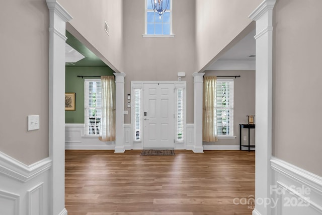10792 Elsfield Ave NW, Concord, NC 28027 - entryway featuring ornate columns, wainscoting, wood finished floors, a decorative wall, and a towering ceiling