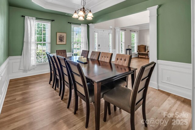 10792 Elsfield Ave NW, Concord, NC 28027 - dining room with ornate columns, a chandelier, ornamental molding, wainscoting, and light wood-type flooring