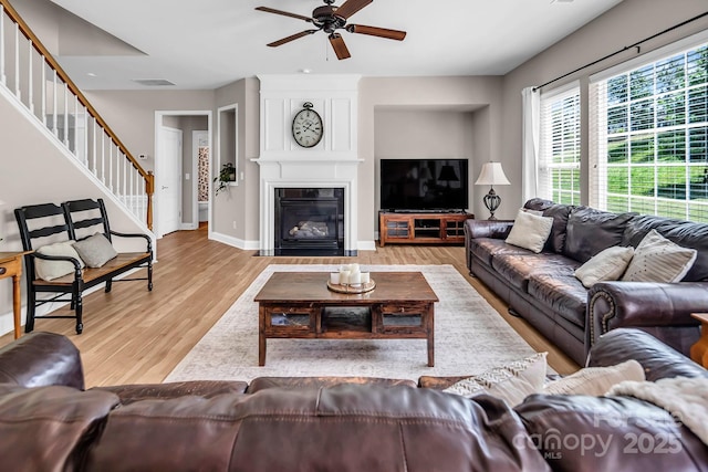 10792 Elsfield Ave NW, Concord, NC 28027 - living room featuring stairs, a ceiling fan, wood finished floors, baseboards, and a large fireplace