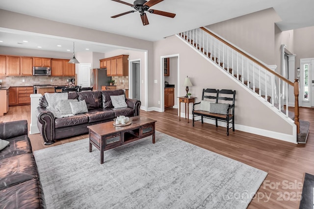 10792 Elsfield Ave NW, Concord, NC 28027 - living room featuring light wood-style flooring, ceiling fan, stairway, baseboards, and recessed lighting