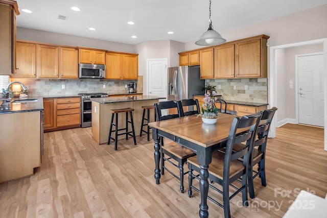 10792 Elsfield Ave NW, Concord, NC 28027 - kitchen with stainless steel appliances, a sink, a center island, decorative backsplash, and light wood-style floors
