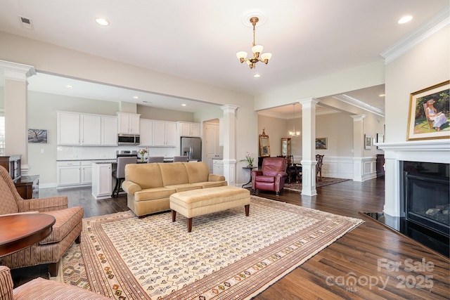 10016 St Kitts Landing Ln, Charlotte, NC 28278 - living room featuring decorative columns, dark wood-style floors, a wainscoted wall, a chandelier, and crown molding