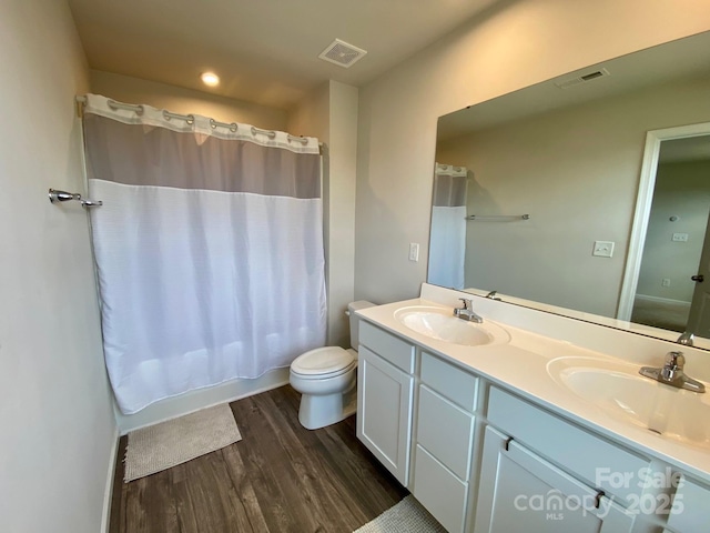 3113 Bouquet St, Charlotte, NC 28215 - bathroom with wood finished floors, double vanity, toilet, shower / bath combo with shower curtain, and recessed lighting