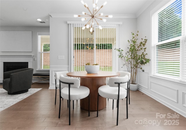 2236 Prairie Rd, Concord, NC 28027 - dining room with a chandelier, light wood-type flooring, a decorative wall, healthy amount of natural light, and crown molding