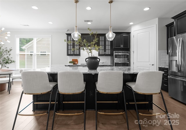 2236 Prairie Rd, Concord, NC 28027 - kitchen featuring appliances with stainless steel finishes, a kitchen island, crown molding, decorative backsplash, and light stone countertops