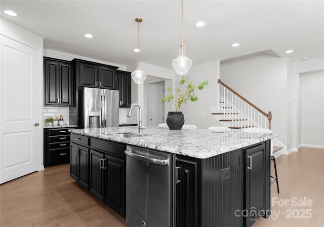 2236 Prairie Rd, Concord, NC 28027 - kitchen featuring appliances with stainless steel finishes, dark cabinets, a sink, light wood-style floors, and recessed lighting