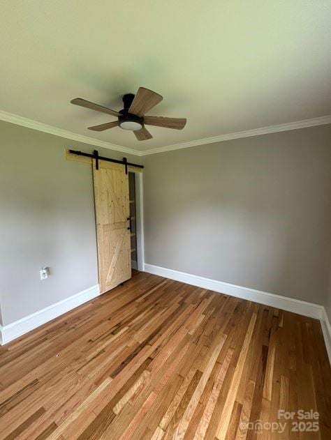 410 Gann St, Lowell, NC 28098 - unfurnished bedroom featuring a barn door, baseboards, crown molding, and wood finished floors