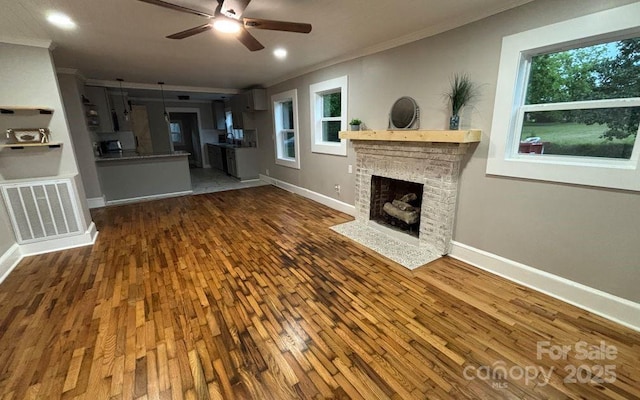 410 Gann St, Lowell, NC 28098 - unfurnished living room featuring ornamental molding, wood finished floors, ceiling fan, a brick fireplace, and baseboards